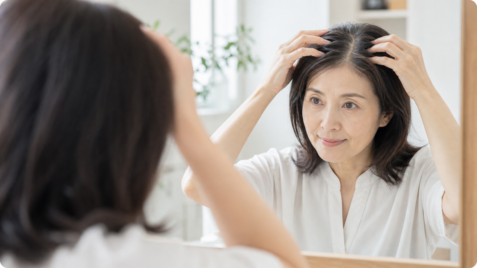 鏡の前で髪の根元を確認する女性